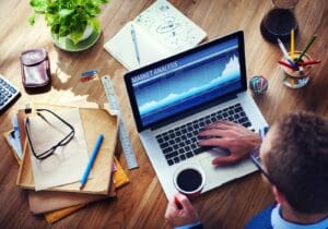 Canadian employee reviewing stock market performance on a laptop computer, while drinking coffee; employee stock options.