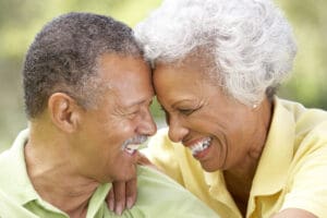 Retired couple laughing together in a park; enjoying the benefits of a Canadian pension plan.