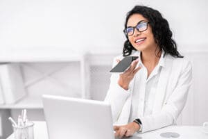Canadian businesswoman consulting with a client via phone while reviewing electronic documents on a laptop computer; e-commerce business in Canada concept.