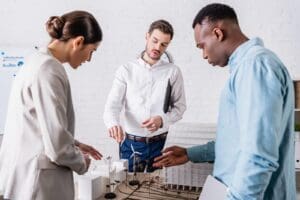 Two men and a woman consider investing as they look at a model for Canadian renewable energy.